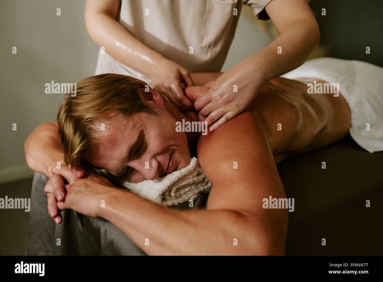Homme souriant pendant un massage relaxant des épaules dans un spa bien-être Banque D'Images