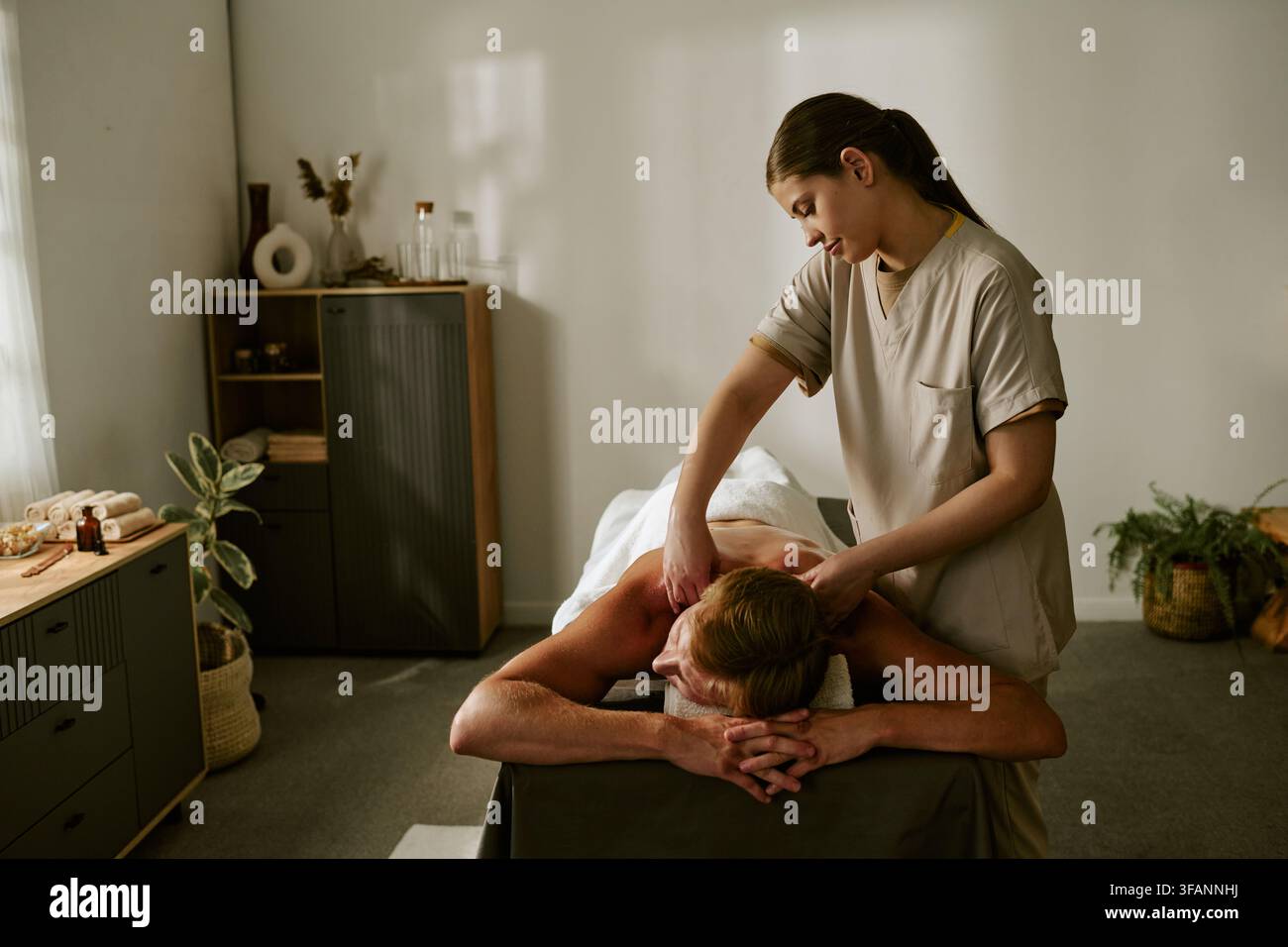 Masseuse massant le dos d'un homme dans un salon de spa bien-être Banque D'Images