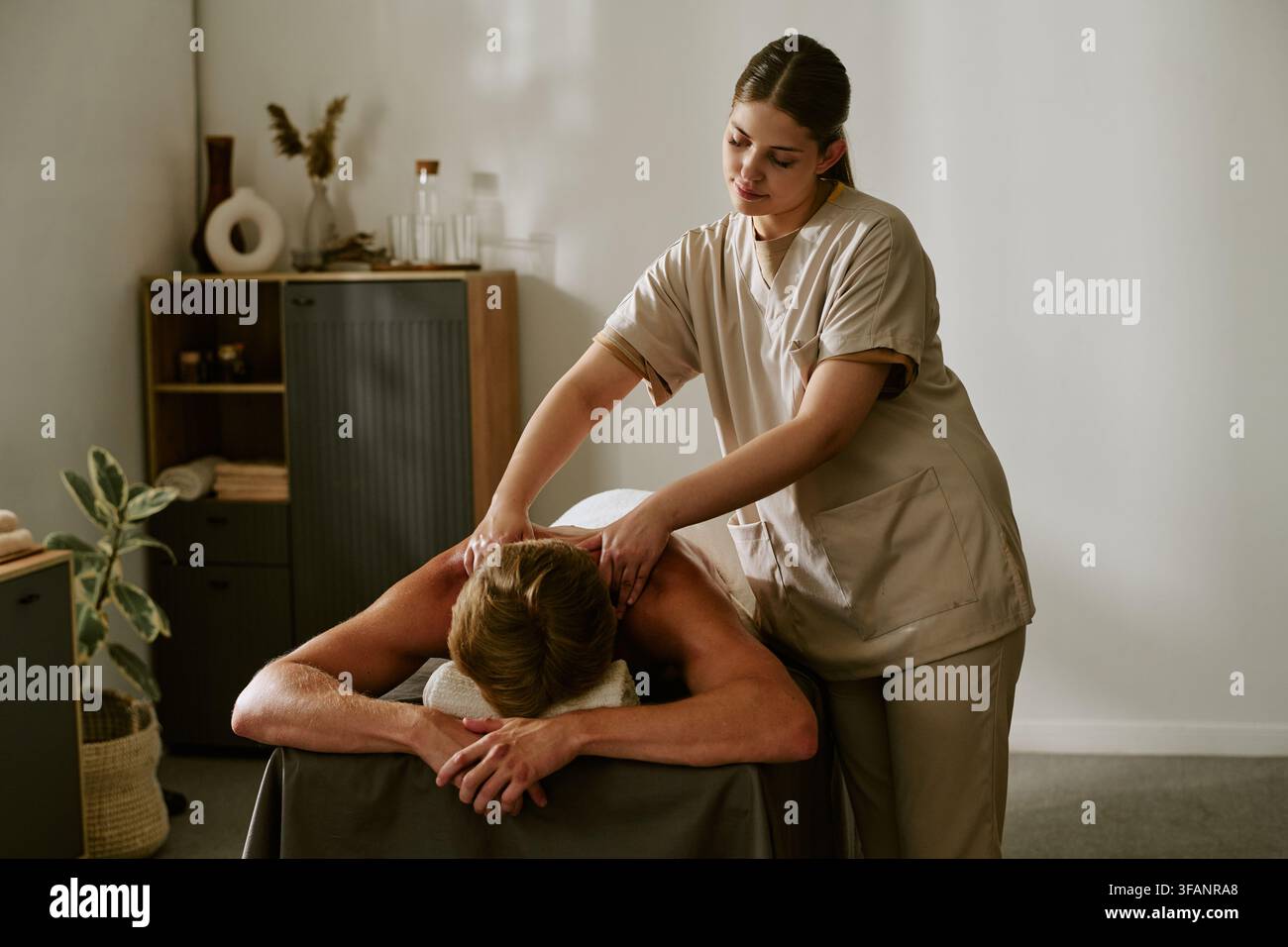 Masseuse féminine massant le dos d'un homme dans un salon de spa bien-être Banque D'Images