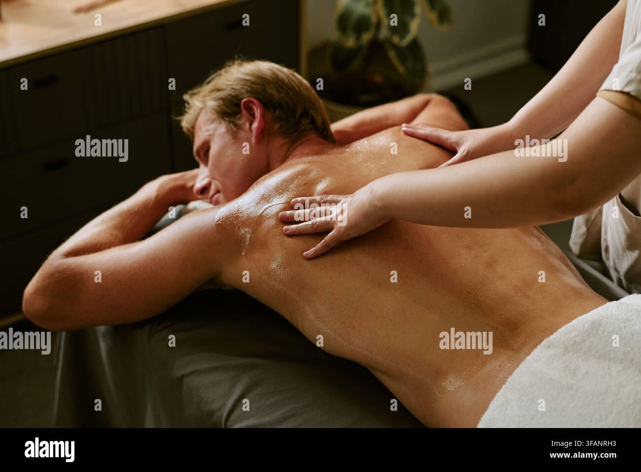 Homme recevant un massage du dos avec de l'huile dans un salon de spa bien-être Banque D'Images