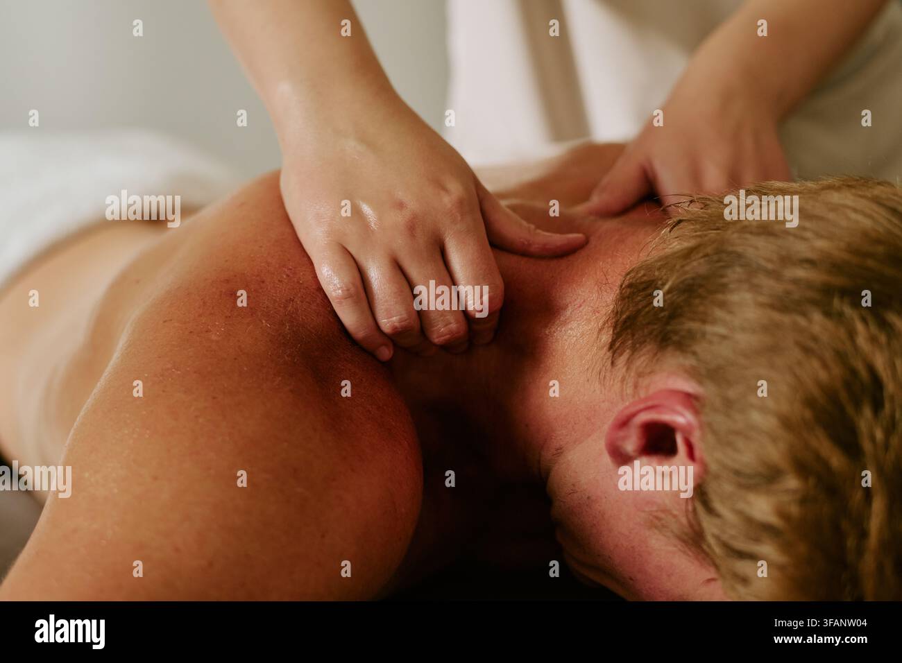 Mains de masseur massant le cou d'un homme dans un centre de bien-être spa Banque D'Images