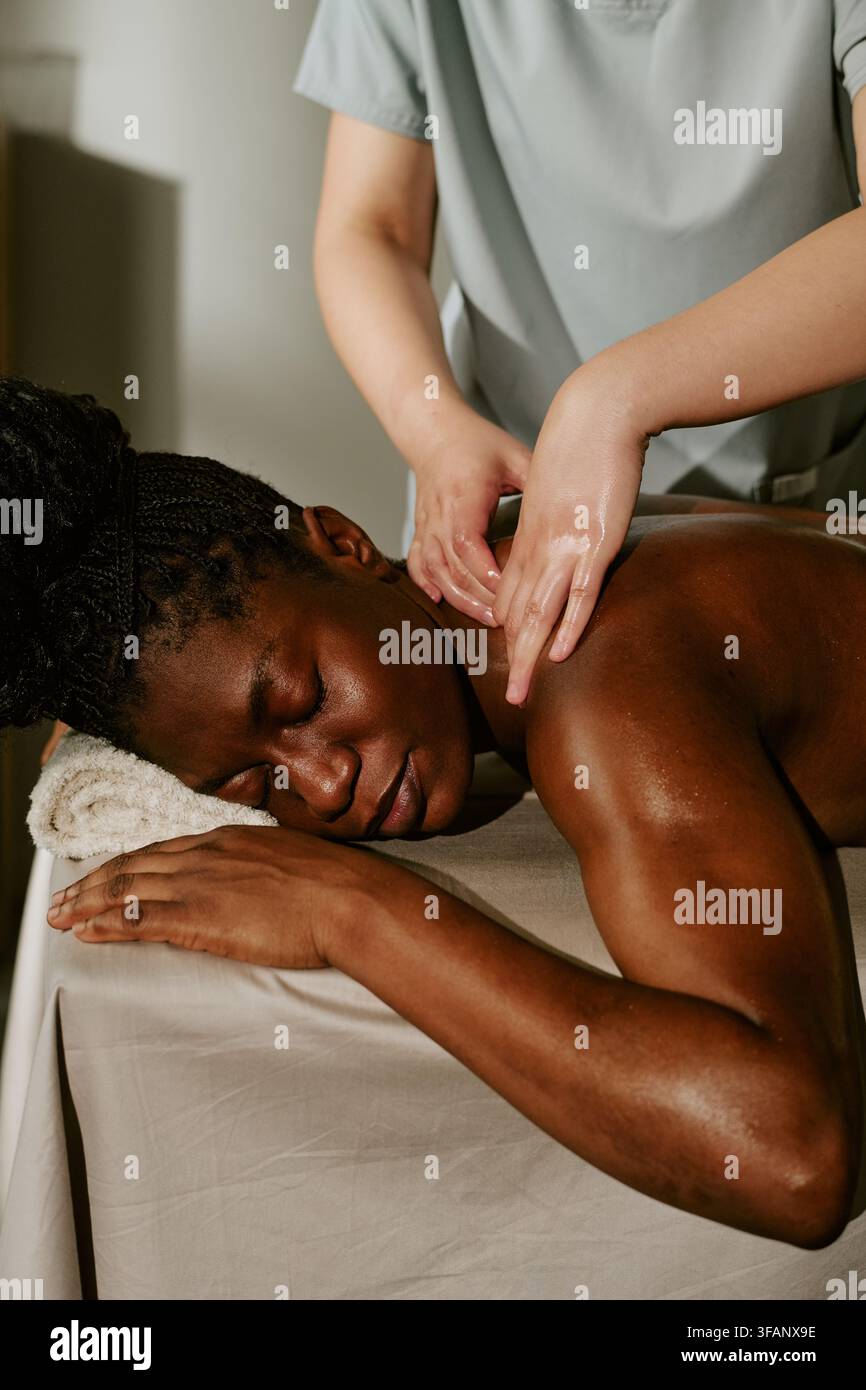 Femme noire recevant un massage relaxant du dos dans un salon de spa bien-être Banque D'Images