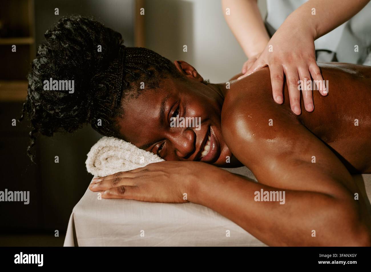 Portrait d'une femme noire souriante recevant un massage du dos dans un spa bien-être Banque D'Images