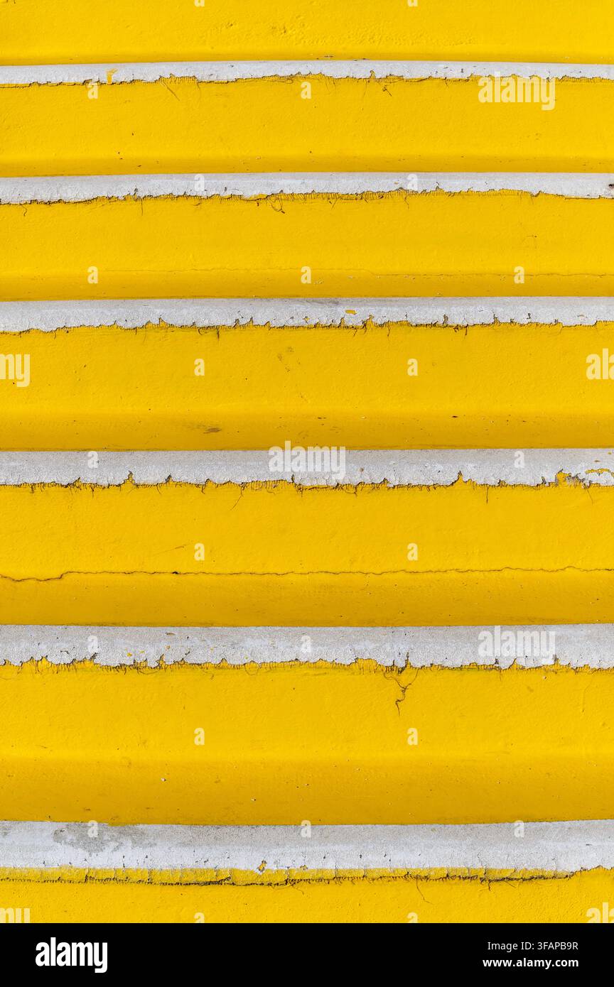 Marches peintes en jaune montrant une surface texturée avec des détails de peinture écaillée Banque D'Images