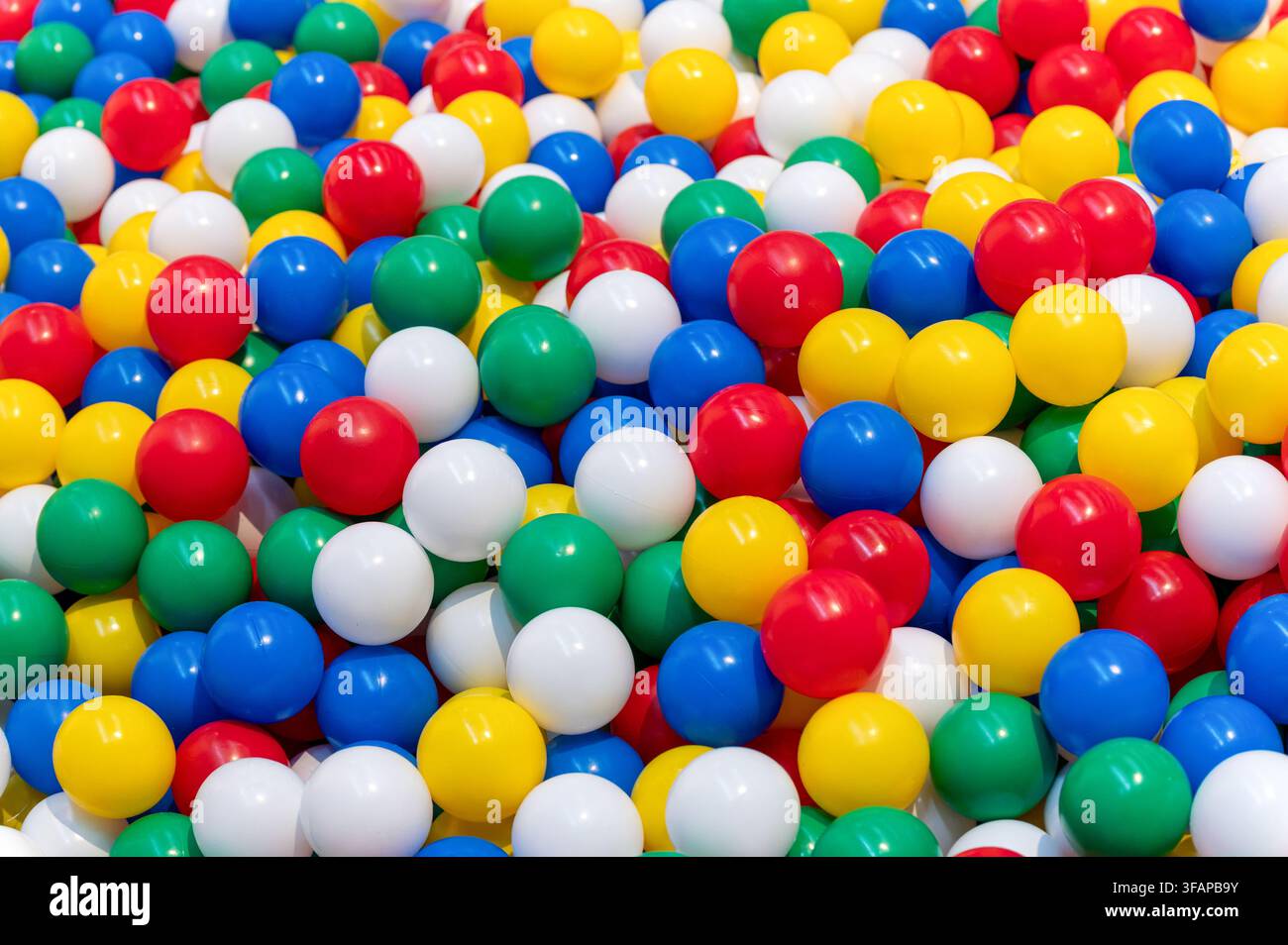 De nombreuses boules en plastique colorées formant un arrière-plan plein cadre ludique et coloré Banque D'Images