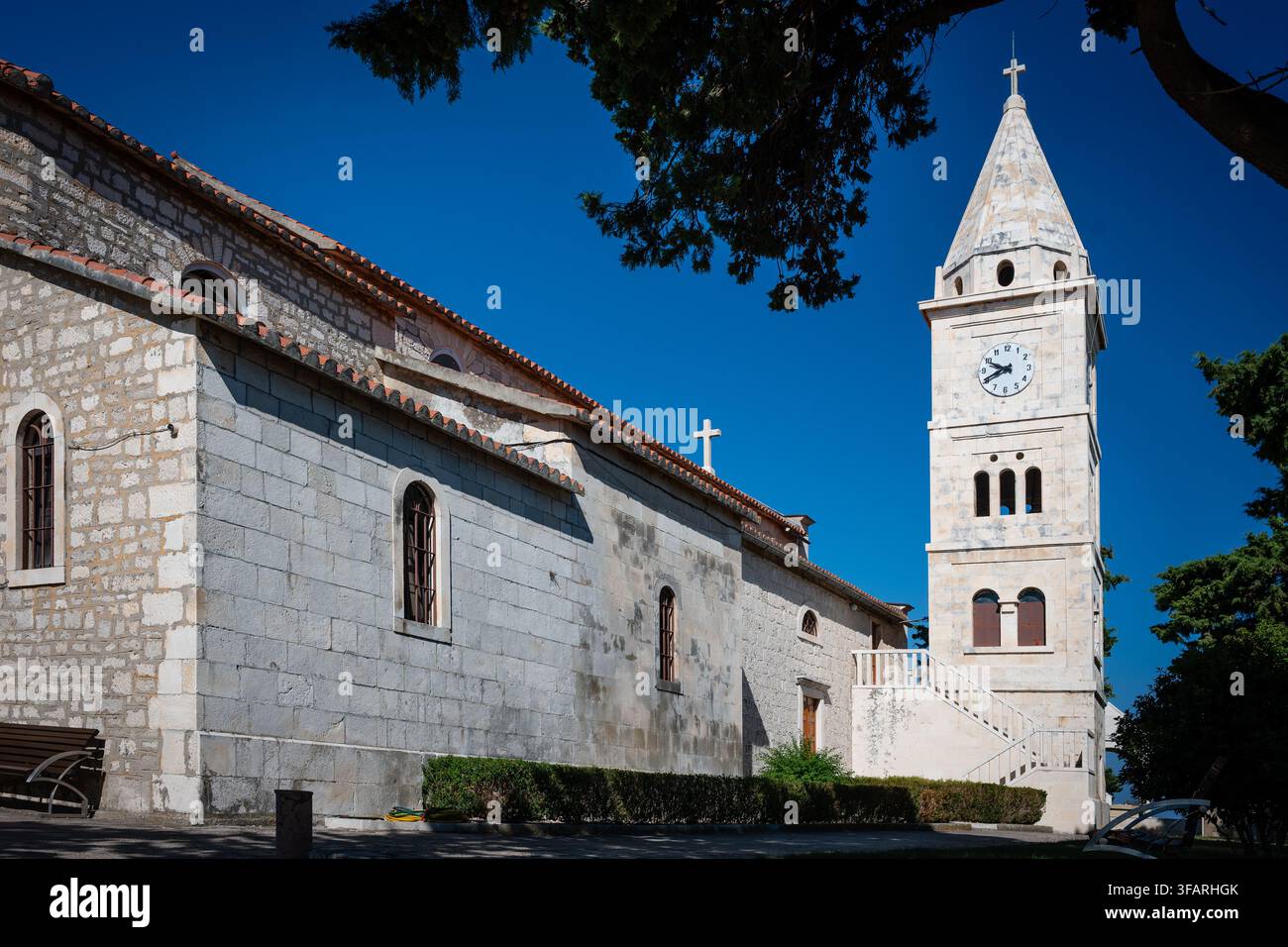 Le clocher en pierre et le beffroi de l'église Saint-Georges sous un ciel bleu clair à Primosten, Croatie Banque D'Images