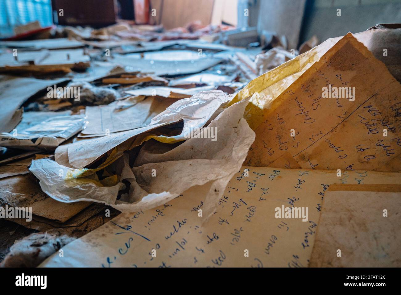 Des papiers manuscrits jaunis gisent parmi les débris sur le sol d'un hôpital abandonné à Chiatura, en Géorgie. Banque D'Images