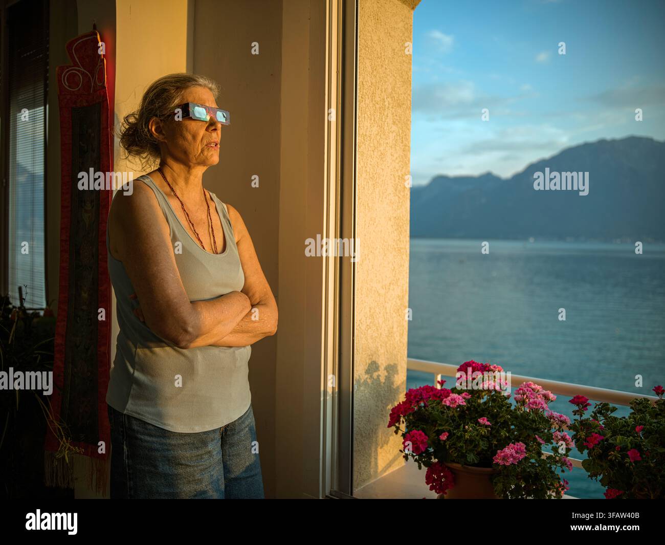 Ma femme Gisela observe l'éclipse quasi totale du soleil depuis notre balcon, Clarens, Montreux, Suisse. 12 août 2026. Banque D'Images