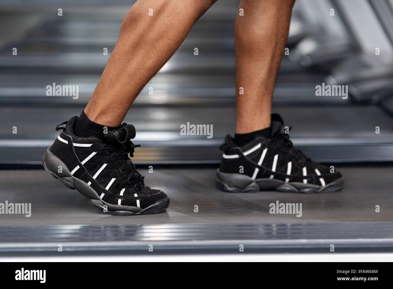 Gros plan des jambes d'homme noir marchant sur un tapis roulant Banque D'Images