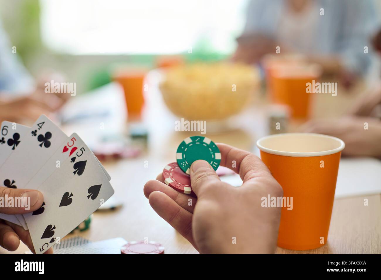 Close-up d'amis jouant au poker avec des cartes et des jetons à une table de fête avec des boissons Banque D'Images