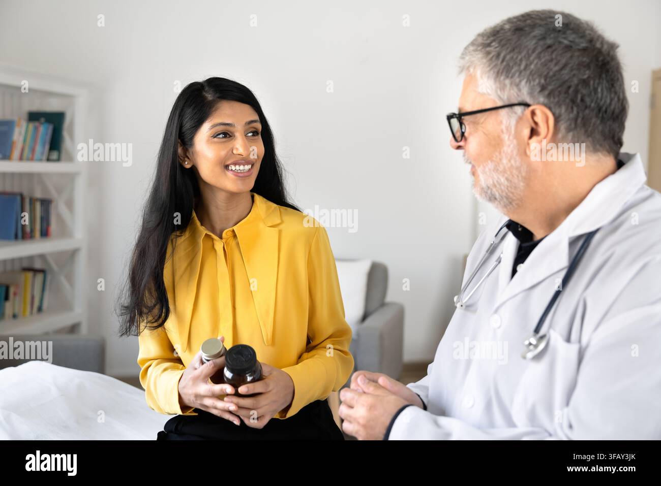 Femme sud-asiatique tenant des flacons de médicaments et discutant avec un médecin masculin Banque D'Images