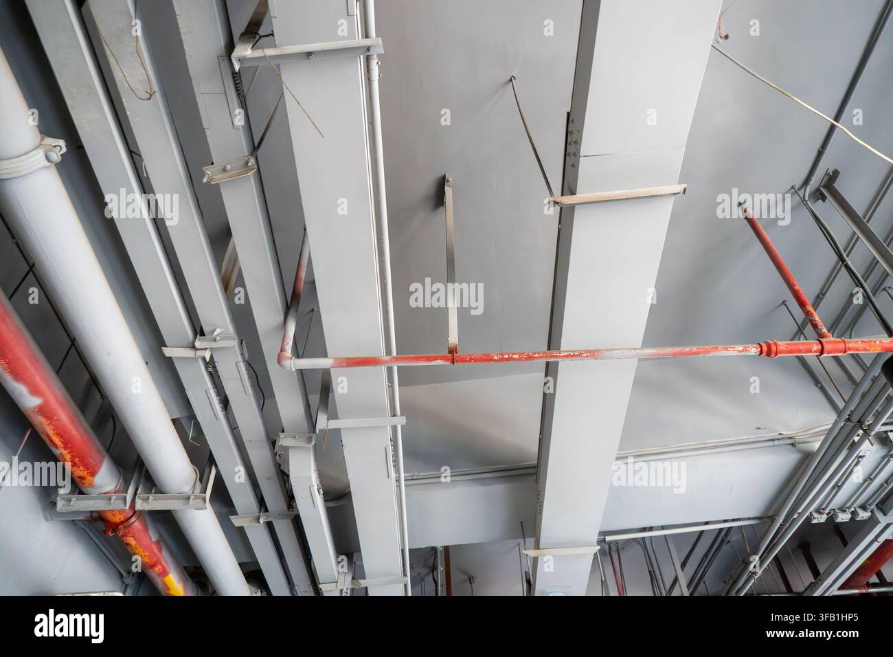 Plafond industriel avec des tuyaux et des poutres apparents. Banque D'Images
