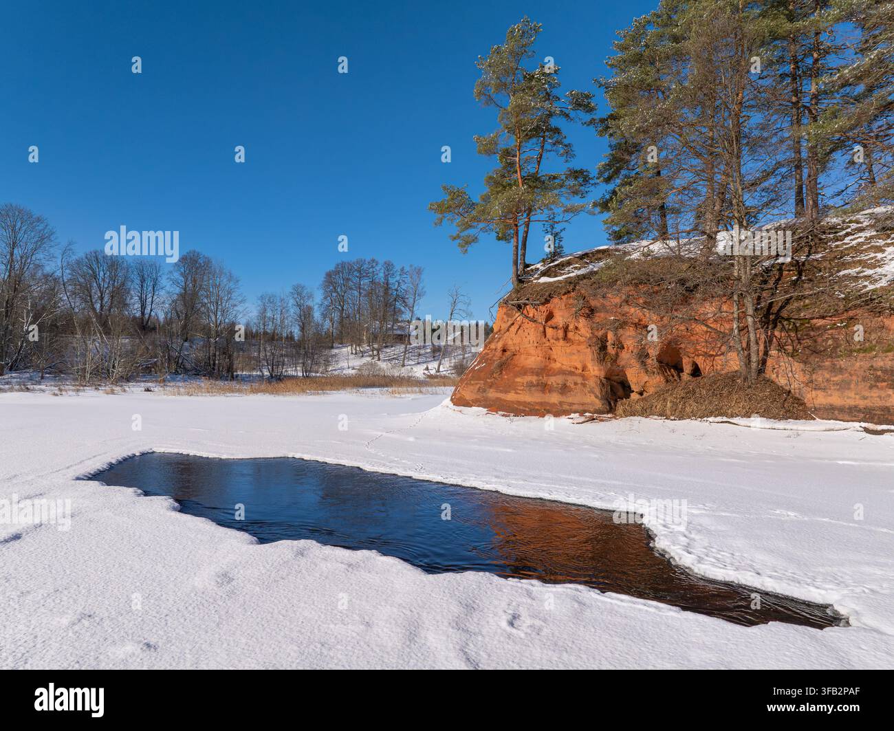 Falaises de grès rouge sur la rivière gelée de Salaca en hiver, Lettonie Banque D'Images