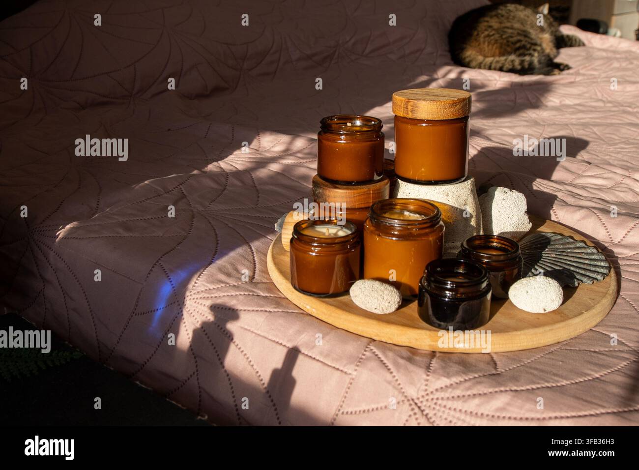 Bocaux ambrés avec couvercles en bois sur le lit. Bocal en verre pour bougies ambrées. Banque D'Images