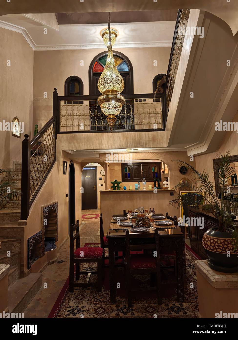 Intérieur traditionnel d'un riad marocain à Marrakech, avec un escalier élégant, des rampes en métal ornées, des lanternes décoratives, un mobilier traditionnel a Banque D'Images