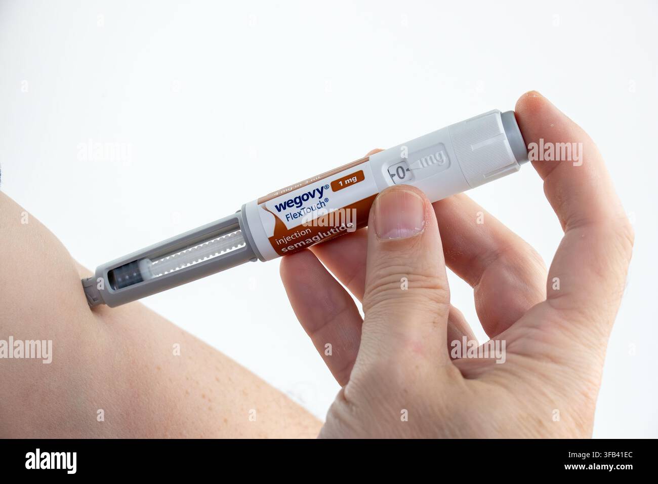 CHESTER, UK, 16 AOÛT 2026 : Une photographie en gros plan en studio d'une main tenant un stylo FlexTouch Wegovy (sémaglutide) de 1 mg pour administrer une subcu Banque D'Images