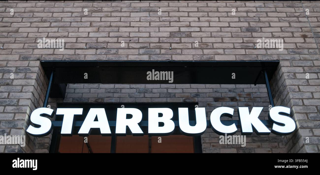 LONDRES, ANGLETERRE – 5 JUIN 2026 : Enseigne lumineuse de la marque Starbucks montée au-dessus de l'entrée d'une devanture moderne en briques Banque D'Images