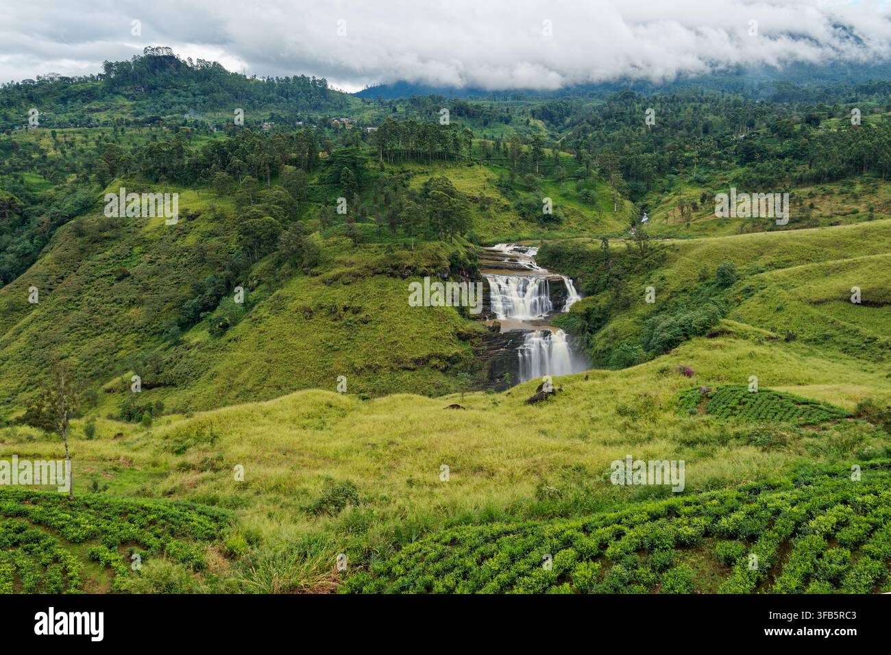 Vue aérienne d'une cascade à plusieurs niveaux dévalant à travers les hautes terres brumeuses du Sri Lanka, les plantations de thé luxuriantes et les collines ondulantes, un paysage tropical pittoresque Banque D'Images