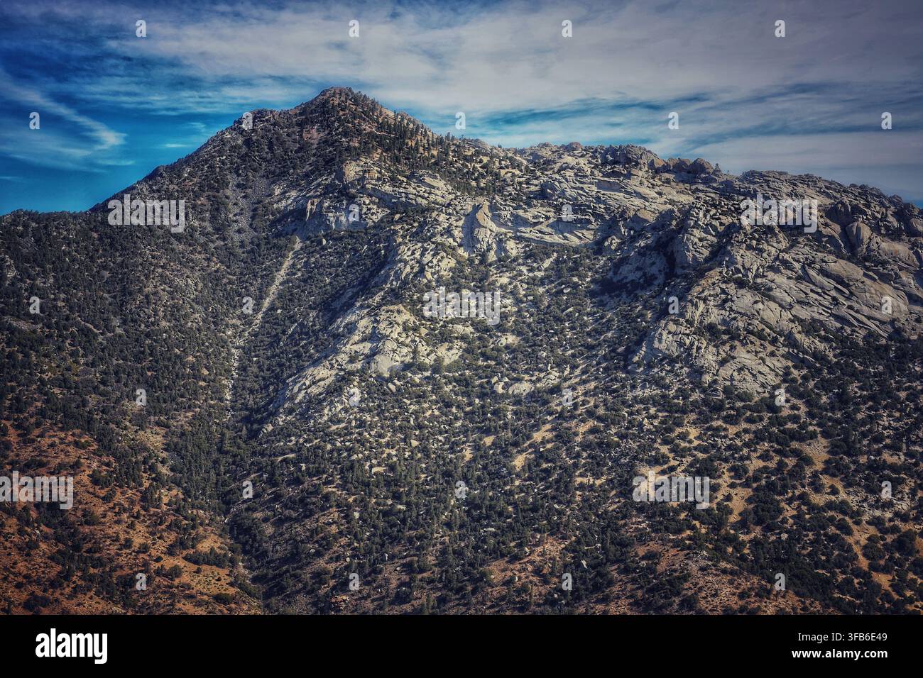 Sommet robuste de Granite Mountain s'élevant au-dessus des pentes désertiques sous des nuages murmurants Banque D'Images