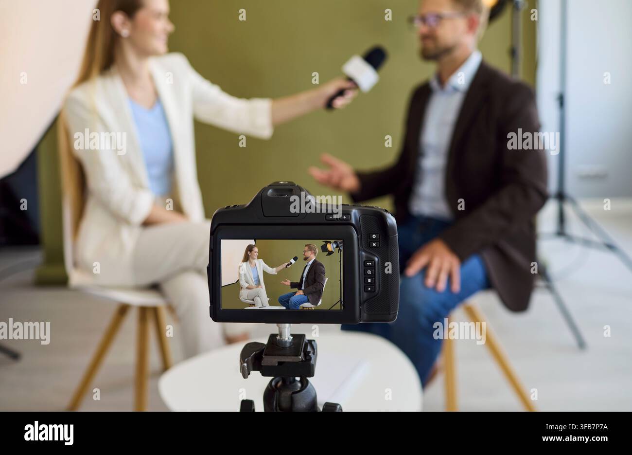 Vue rapprochée d'une caméra enregistrant un journaliste interviewant un invité dans un studio moderne Banque D'Images
