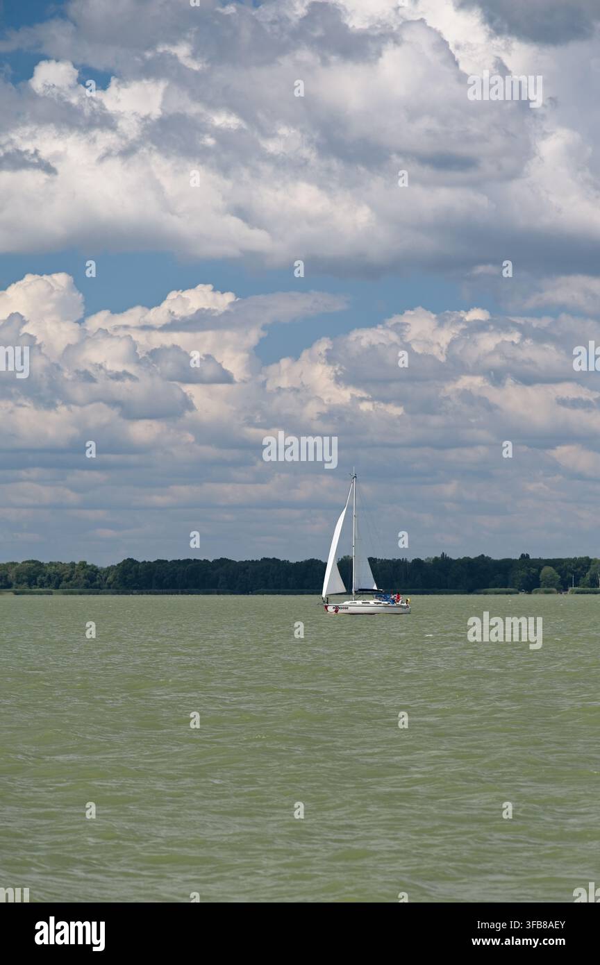 Keszthely, Hongrie – 24 juillet 2026 : Voilier blanc naviguant sur le lac Balaton sous des nuages d'été dramatiques. Banque D'Images