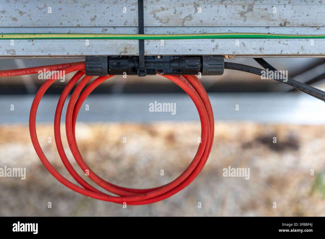 Détail de fils rouges et noirs connectés à une boîte de jonction de panneau solaire avec un fil de terre vert au-dessus Banque D'Images