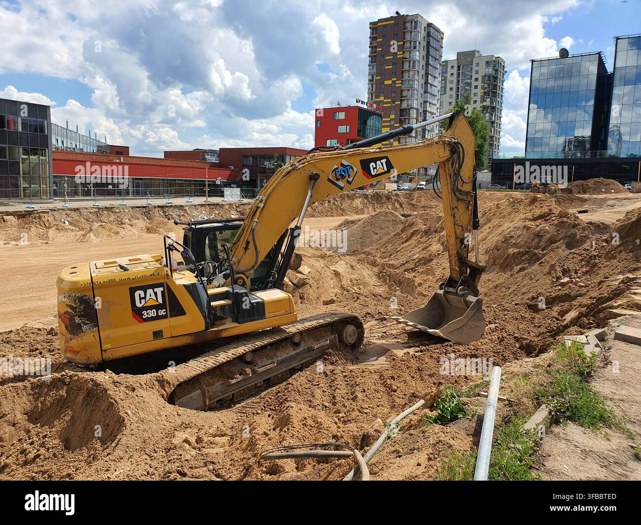 Une pelleteuse Caterpillar 330 GC jaune est positionnée sur un chantier de construction, creusant dans un sol sablonneux. La pelleteuse hydraulique arbore le logo CAT Banque D'Images
