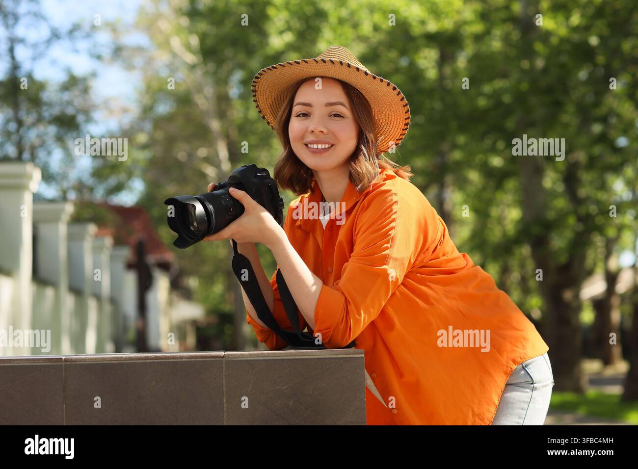 Photographie de voyage et aventure en plein air, jeune femme avec appareil photo et chapeau de paille souriant dans un parc Banque D'Images