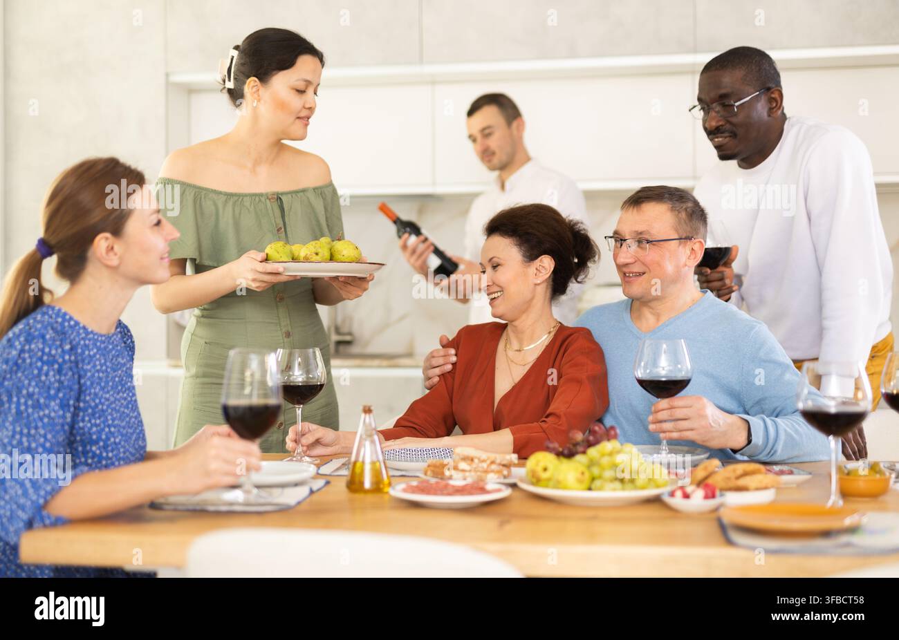 Les compagnons se sont rassemblés autour d’une table festive, participant à des discussions animées et dégustant les délices du vin rouge Banque D'Images