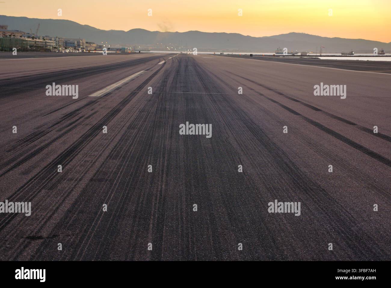 Piste d'atterrissage de l'aéroport avec des traces de pneus au coucher du soleil. Banque D'Images