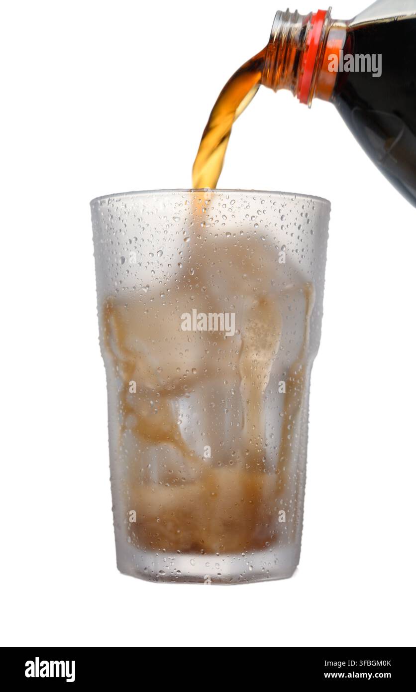 Photo d'action puissante montrant un liquide Coca-Cola sortant d'une bouteille dans un verre rempli de glace, capturé à mi-versement sur fond blanc propre. Phot énergie de marque Banque D'Images