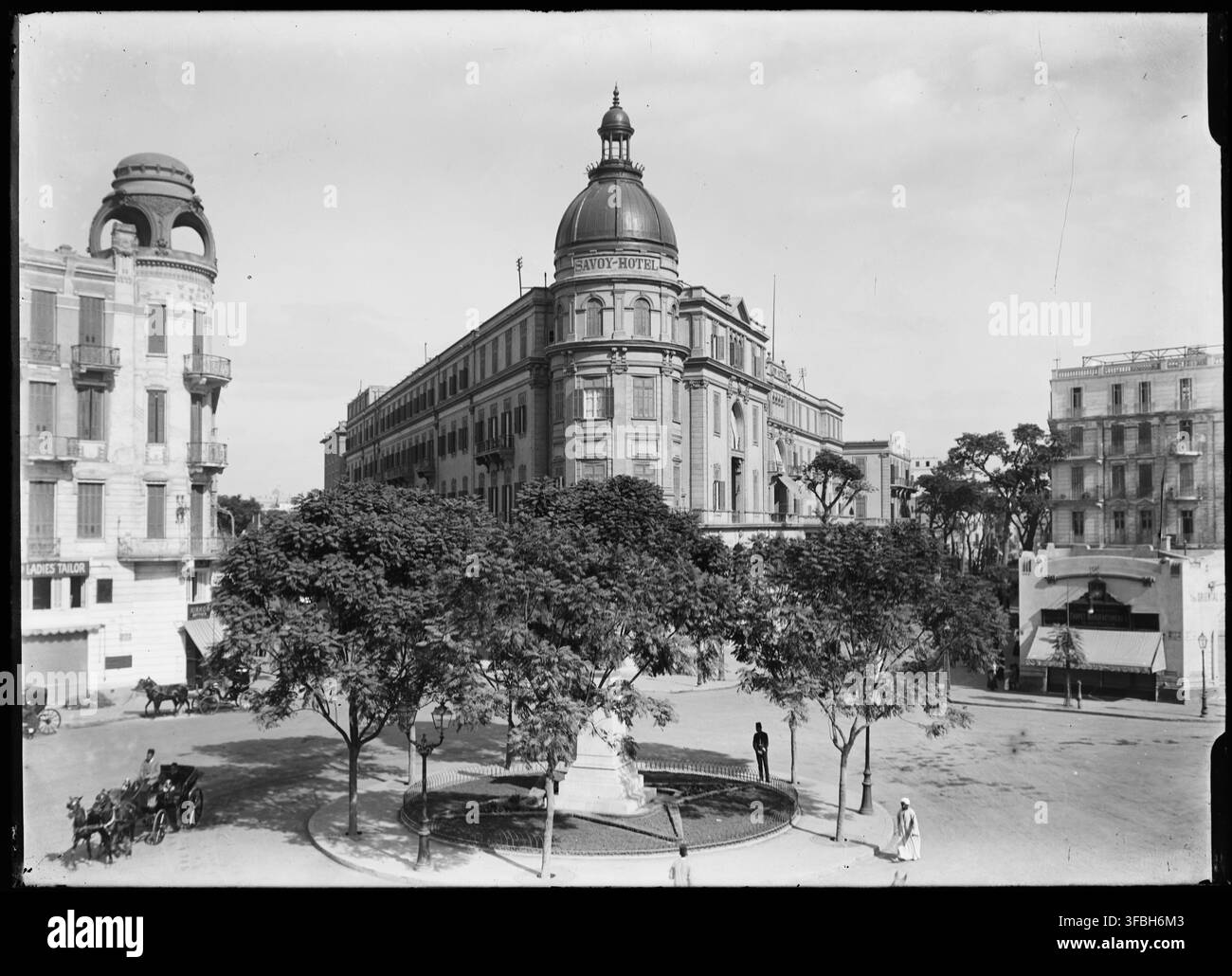 L'hôtel Savoy dans un cadre urbain du Caire, en Égypte, avec une enseigne indiquant « SAVOY-HOTEL / TAILLEUR POUR DAMES », sur une photographie de 1910 montrant le paysage urbain de l'époque. Banque D'Images