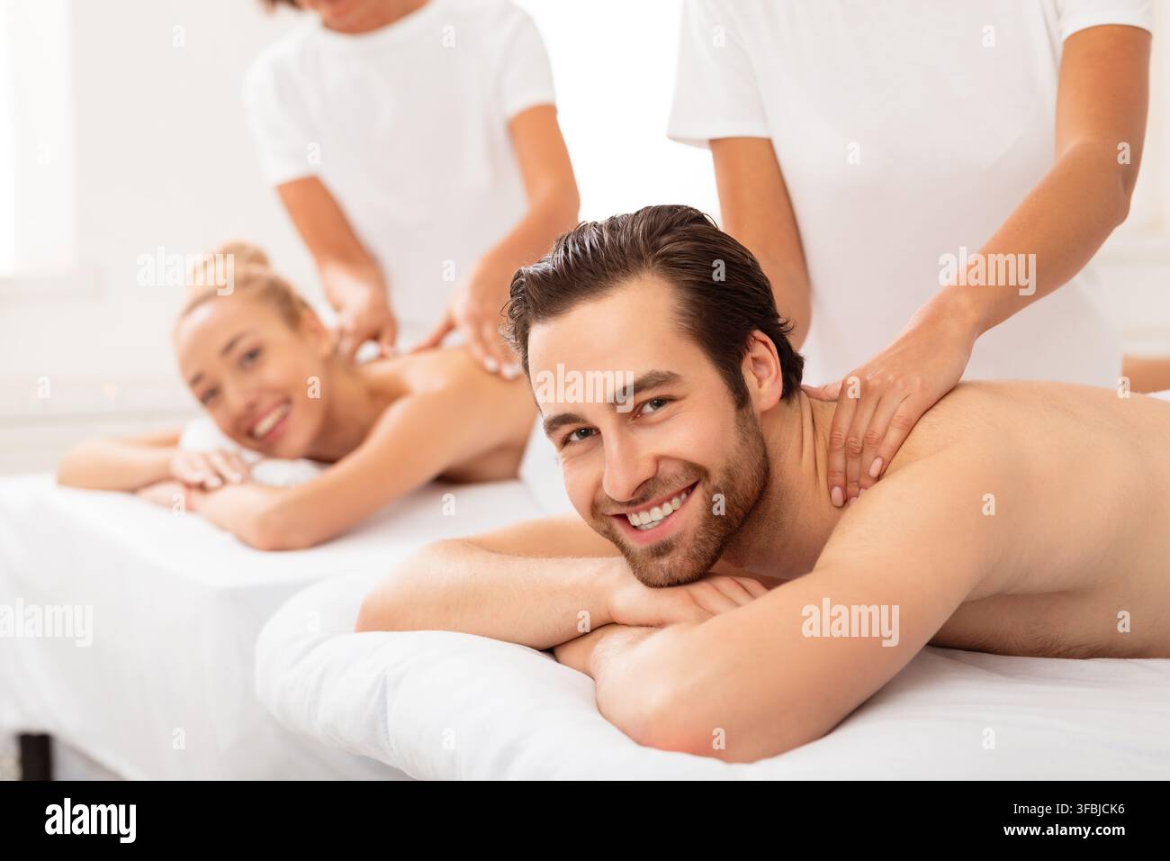 Couple joyeux recevant un massage du cou au spa Banque D'Images