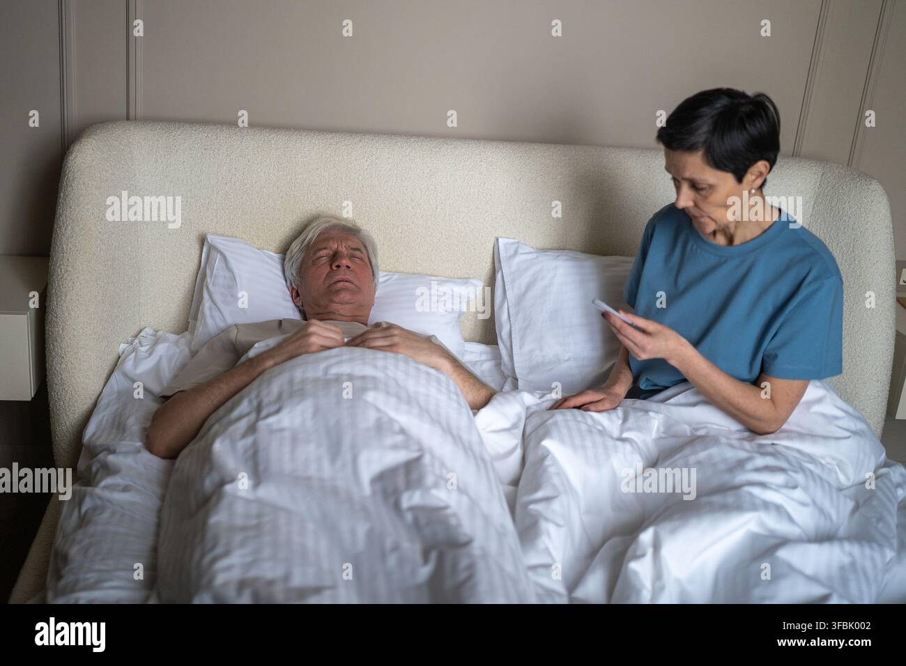 La femme mature anxieuse prend la température du mari fiévreux malade dans le lit avec thermomètre. Moniteur de santé Banque D'Images