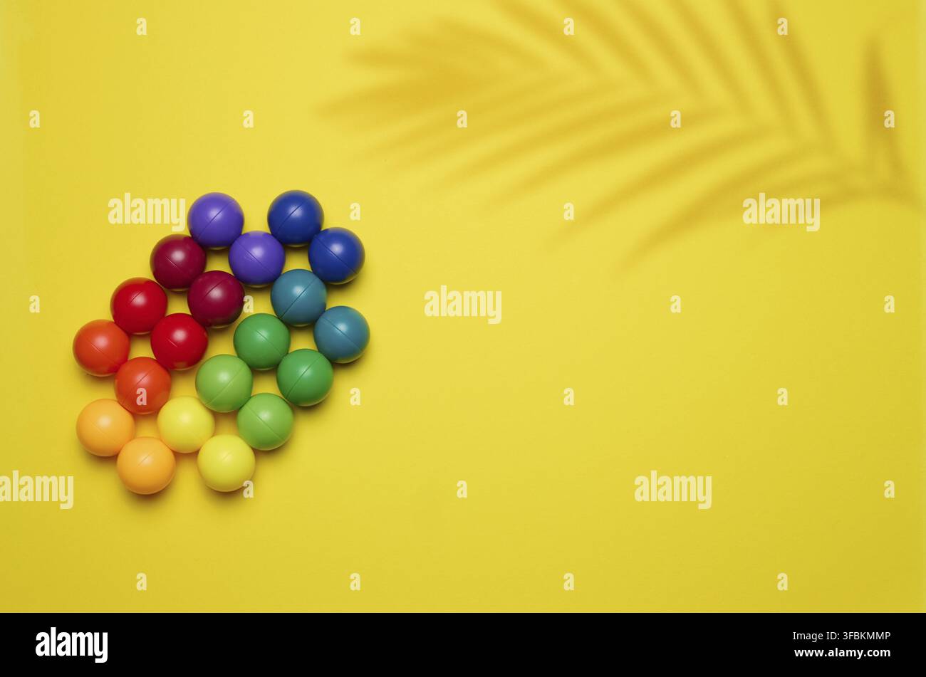 Fond abstrait avec des boules en plastique multicolores sur un fond jaune, une scène pour la démonstration de cosmétiques et de produits Banque D'Images