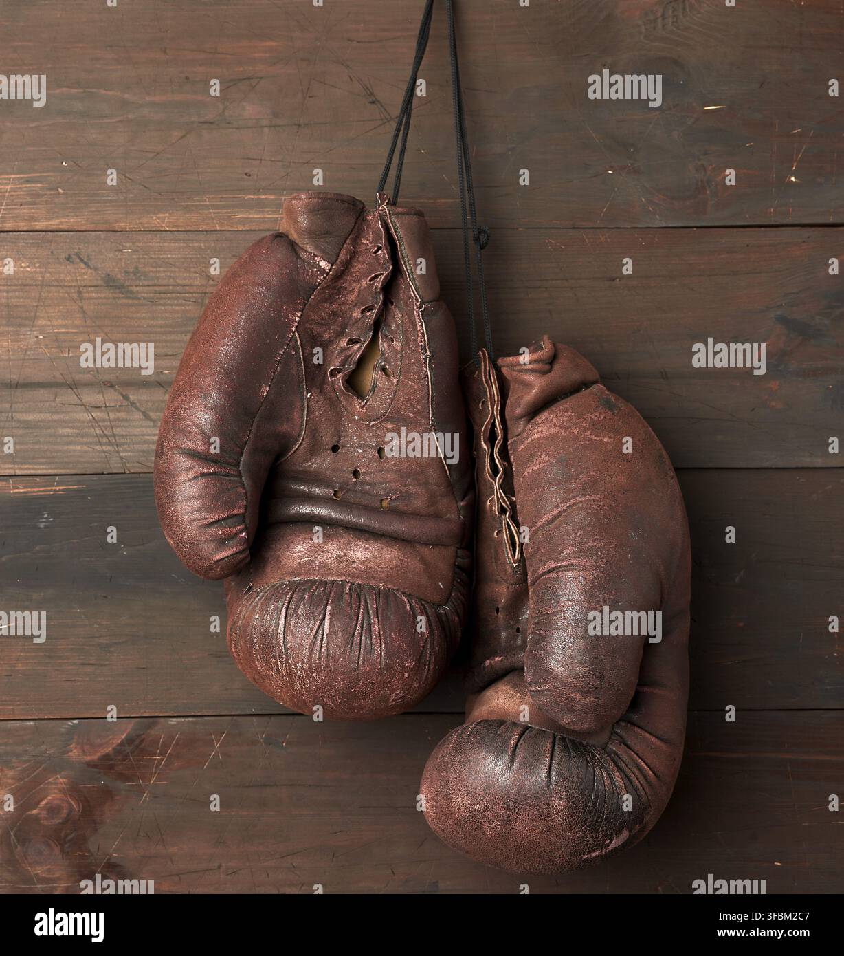 paire de gants de boxe en cuir marron accrochés à un mur en bois, équipement de sport Banque D'Images