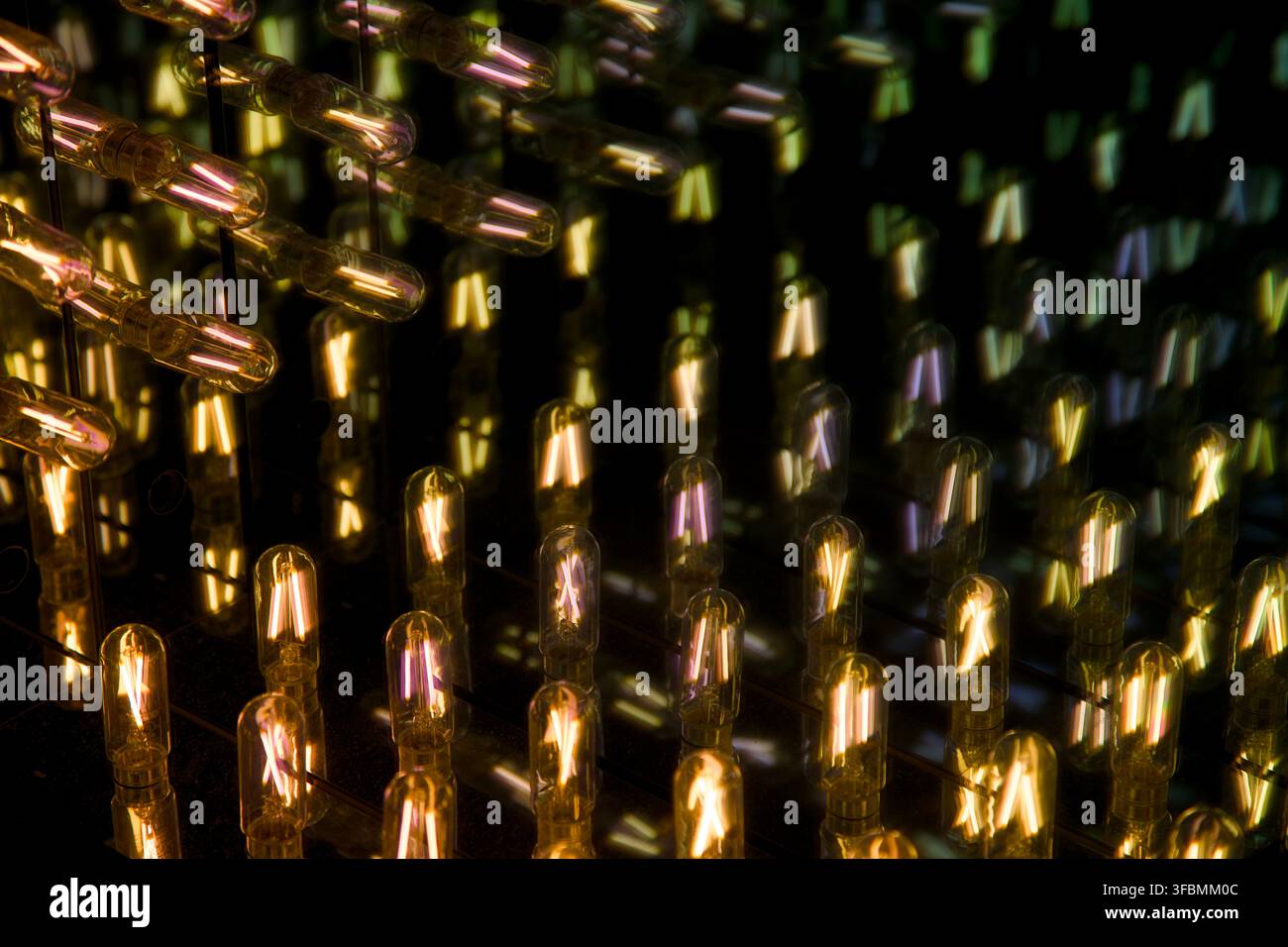 Réflexion infinie d'ampoules à filament lumineux à l'intérieur d'un miroir infini, montrant des motifs de lumière à décalage de couleur répétitifs. Banque D'Images