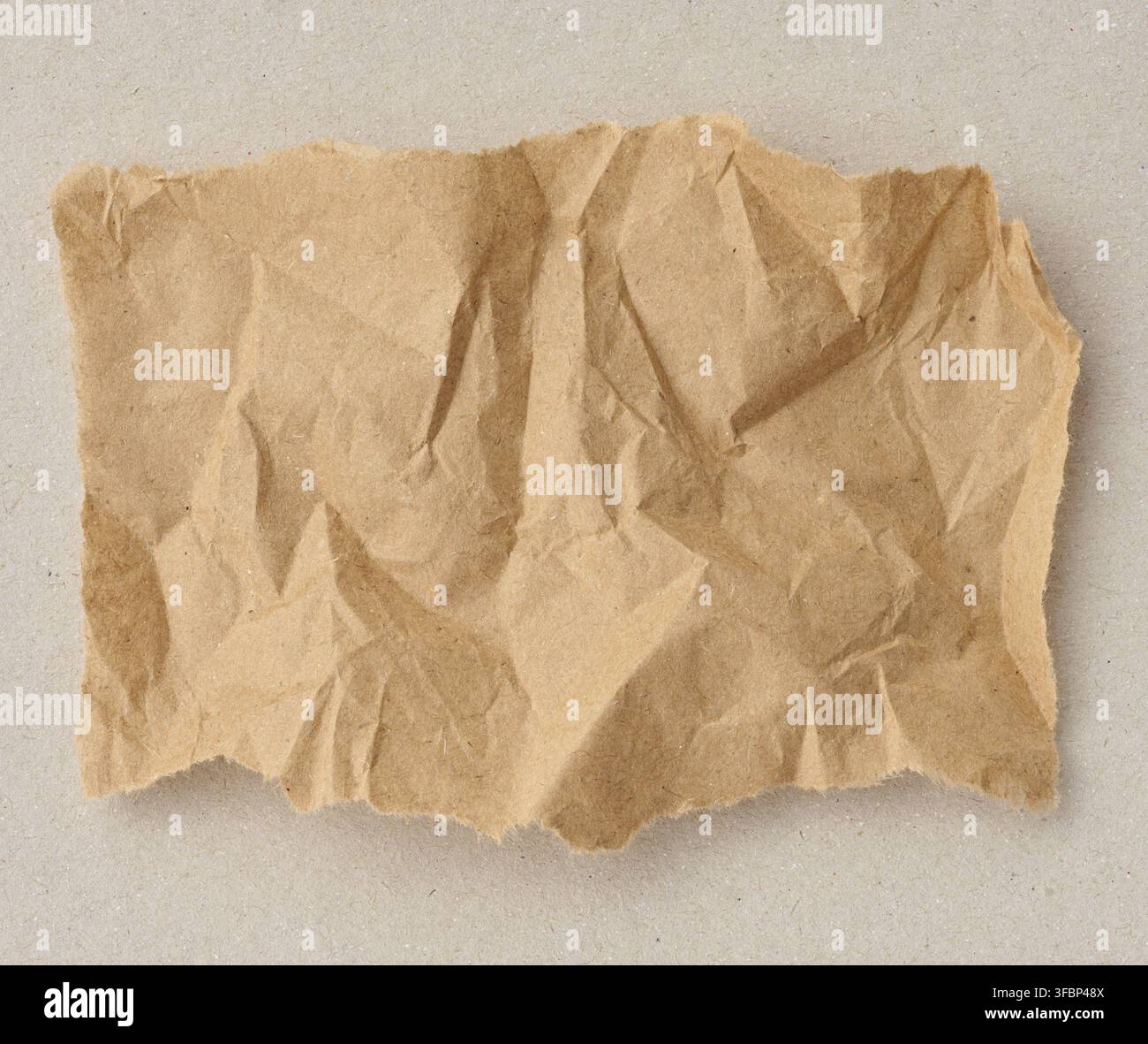 Un morceau déchiré de papier artisanal brun froissé sur un fond de carton gris. Copier l'espace Banque D'Images