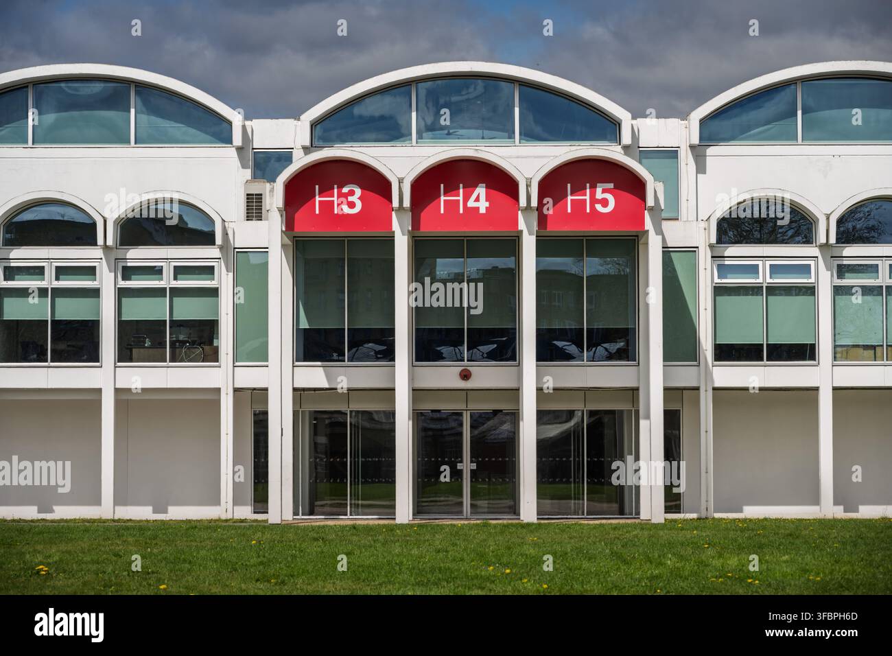 Une vue avant rognée de l'entrée en verre des hangars 3, 4 et 5 du musée de la RAF à Londres, mise en valeur par des panneaux signalétiques rouges saillants Banque D'Images
