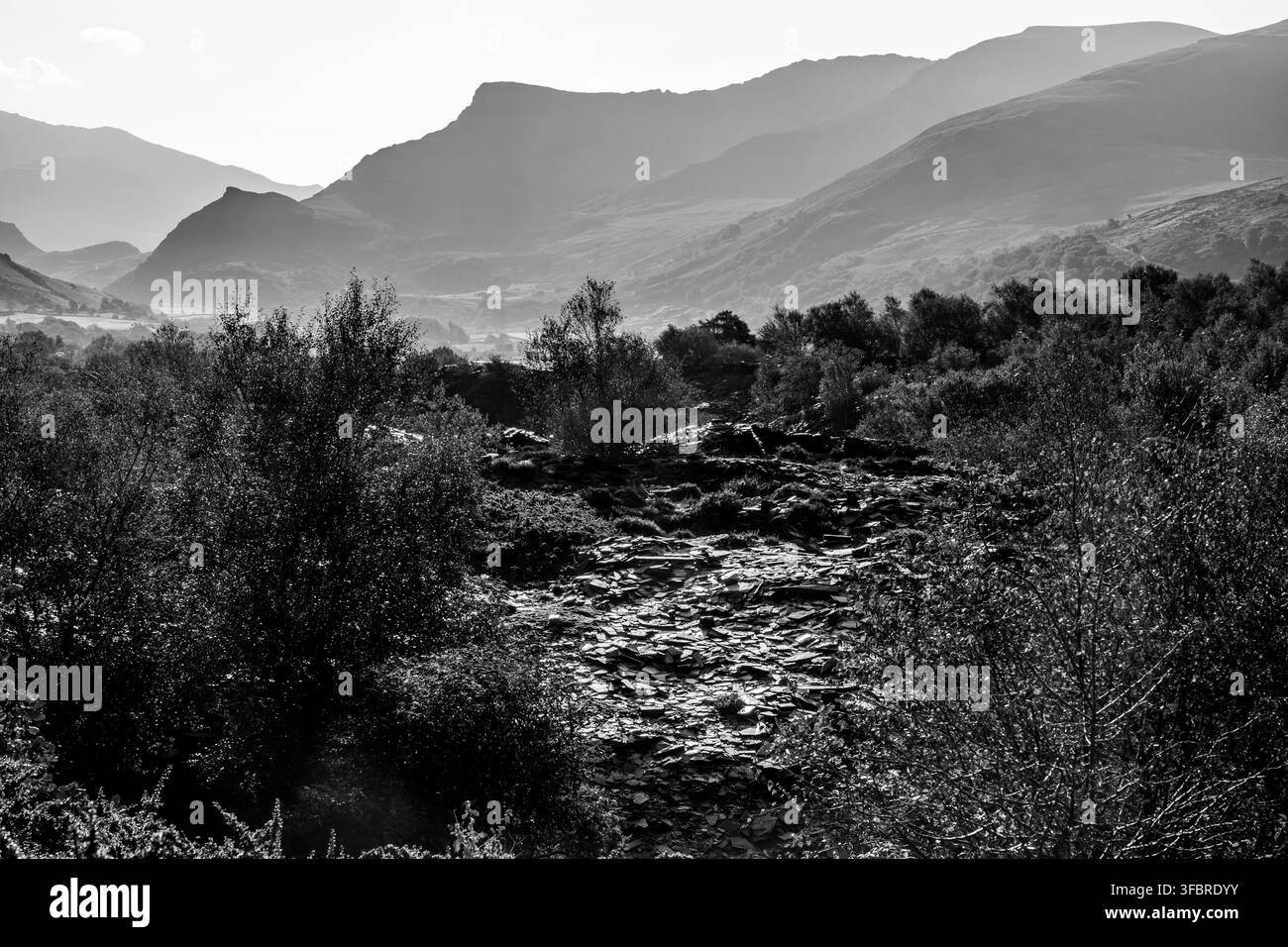 Vue en noir et blanc à travers les déchets de carrière d'ardoise vers les montagnes lointaines de la vallée de Nantlle depuis la carrière Dorothea Banque D'Images