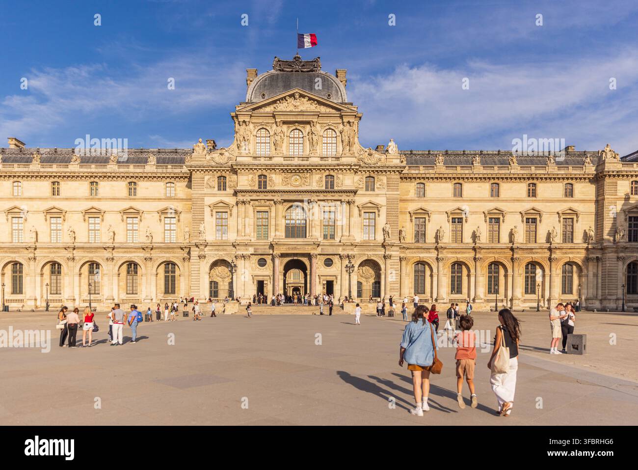 PARIS, FRANCE - 20 JUIN 2026 : Les touristes traversent la Cour Napoléon en direction du Pavillon Sully du musée du Louvre. Banque D'Images
