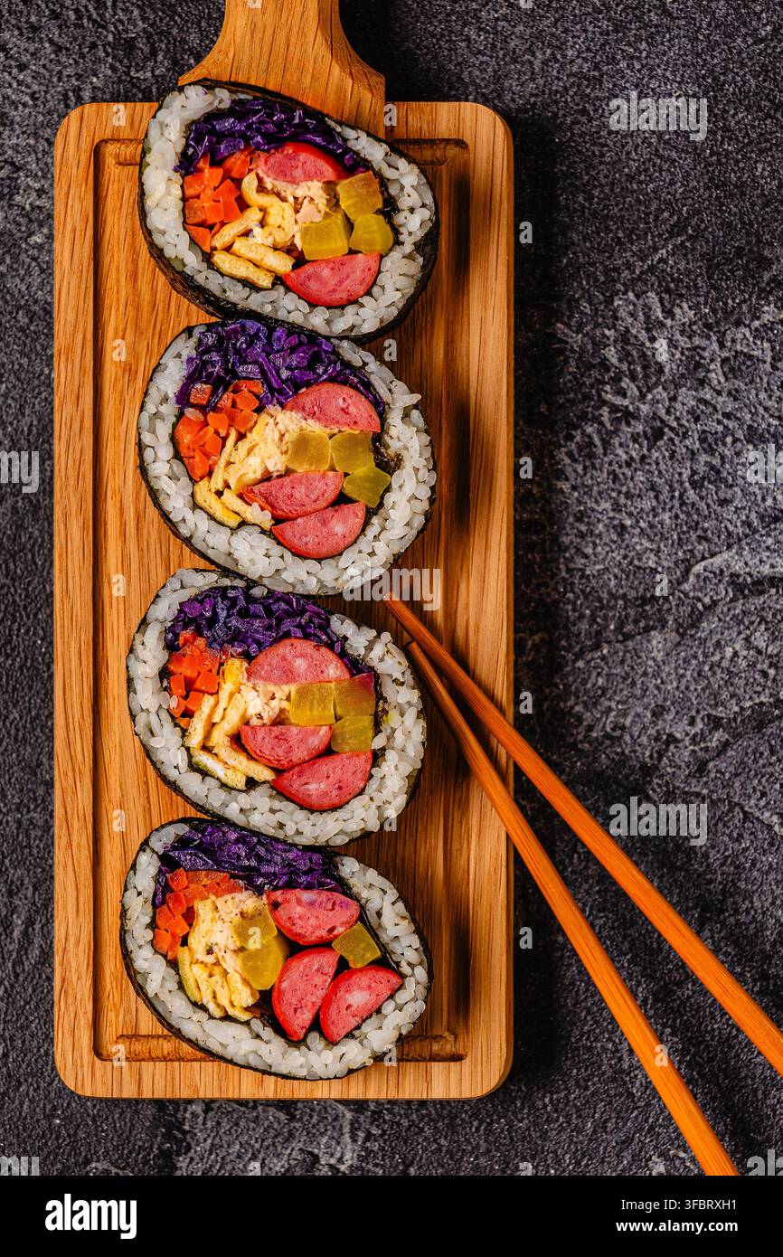 Kimbap (ou gimbap) avec des ingrédients colorés servis sur une planche en bois Banque D'Images