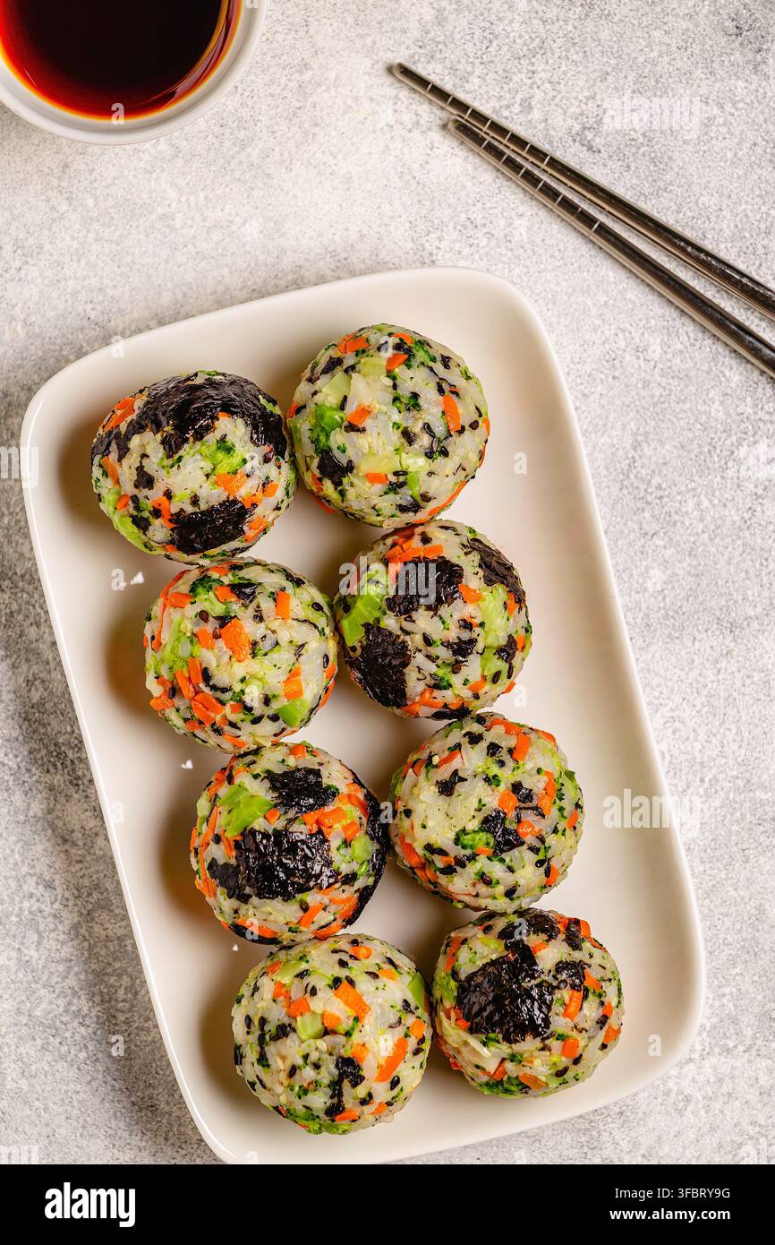Boulettes de riz coréennes (jumeokbap) avec légumes servis avec sauce dans une assiette, vue de dessus. Banque D'Images