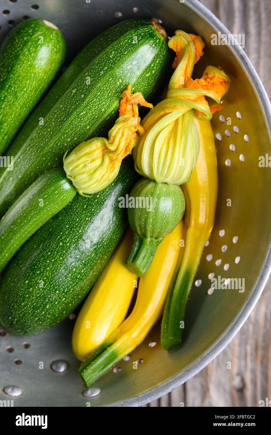 Assortiment de courgettes avec des fleurs dans un panier, légumes biologiques frais, concept de ferme à table. Courgettes vertes et courgettes jaunes vue de dessus, composition propre, ingrédient sain Banque D'Images