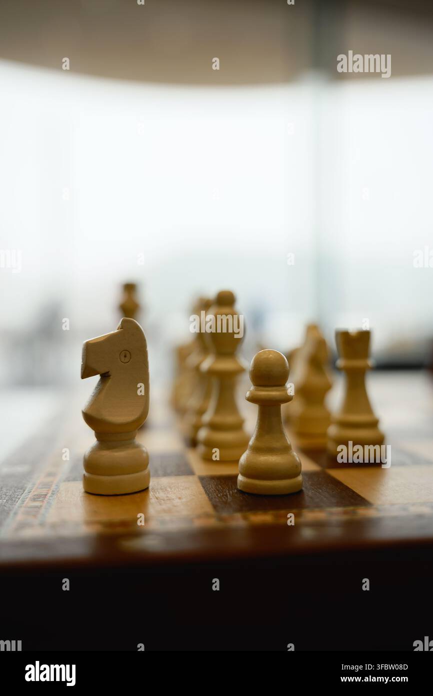 Helsinki, Finlande - 1er mars 2026 : des pièces d'échecs en bois sont posées sur un échiquier sous une lumière douce à l'intérieur. Banque D'Images
