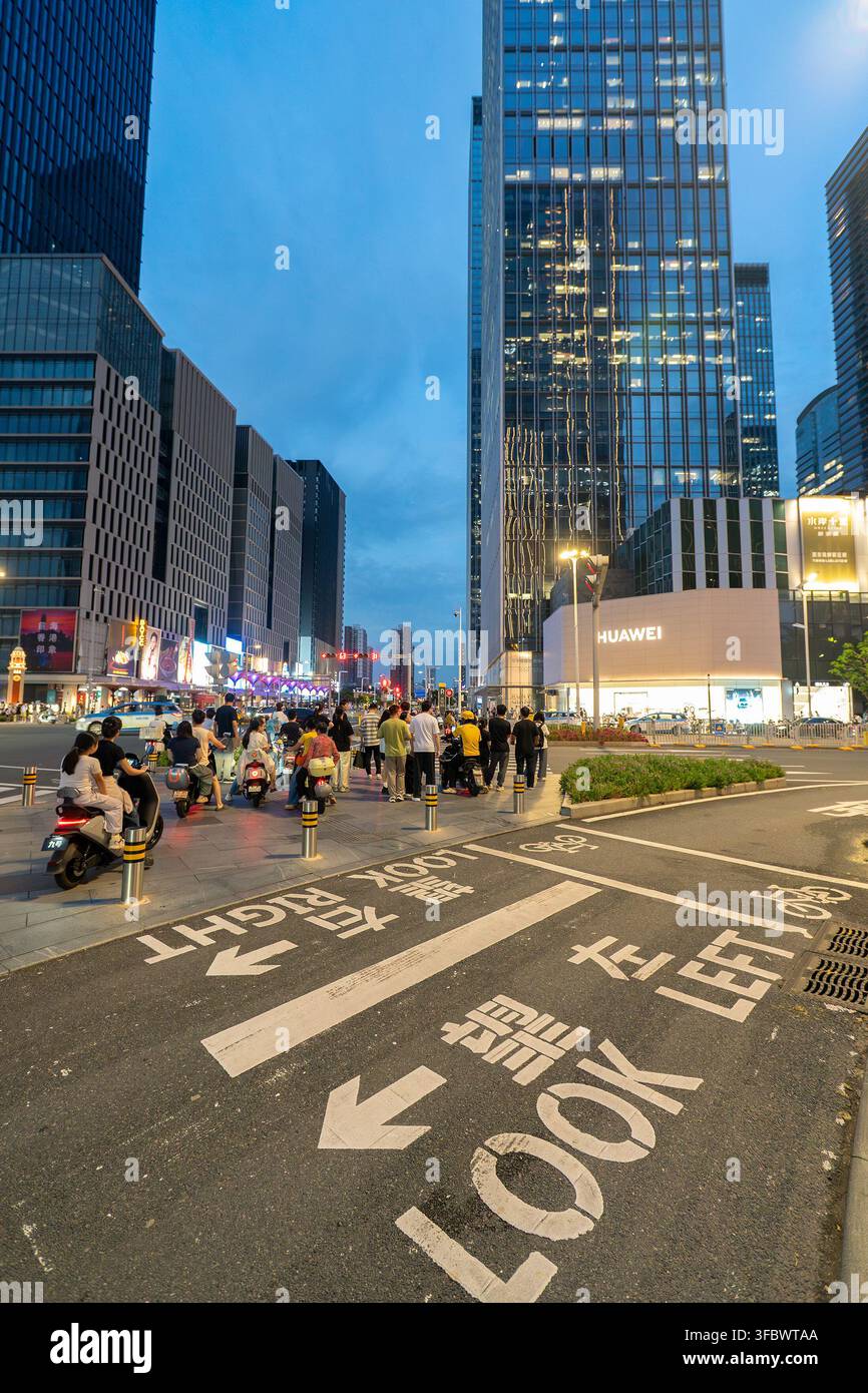 Shenzhen, Chine – 27 juillet 2026 : Des personnes à une intersection avec des marquages routiers de style Hong Kong à Hong Kong Charm dans la zone de Qianhai au crépuscule. Banque D'Images