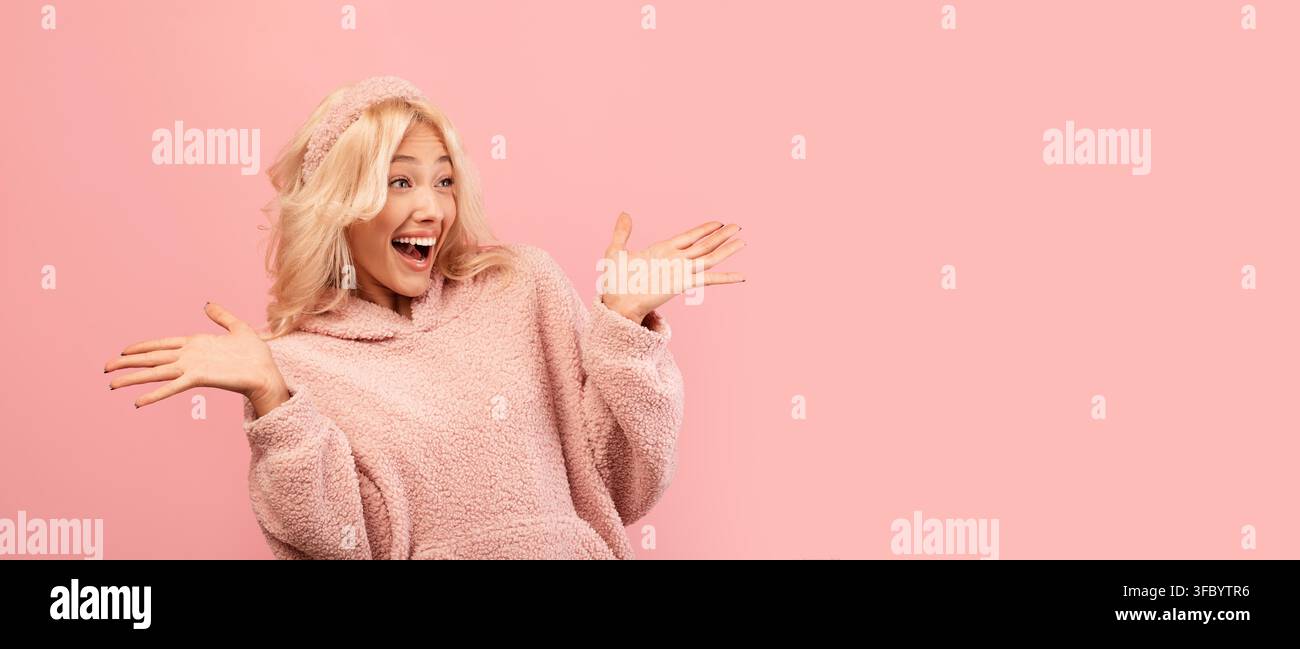 Jeune femme heureuse souriant et gesticulant les bras grands ouverts sur fond rose Banque D'Images