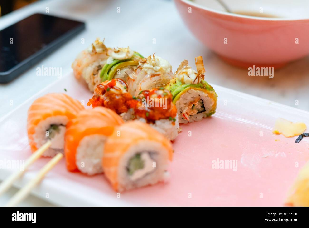 Configuration complète pour un dîner sushi avec baguettes dans un restaurant paisible. Mise en place détendue mettant en avant des plats japonais frais prêts à être dégustés. Composition appétissante d'un repas invitant à un dîner calme avec des fruits de mer Banque D'Images