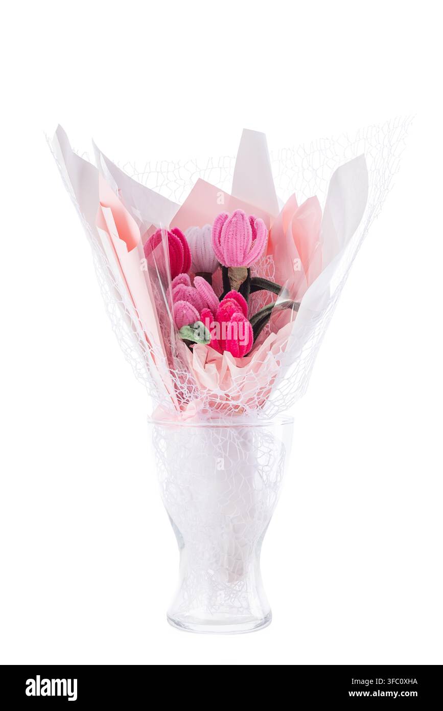 Bouquet de tulipes en nettoyeur de pipe fait à la main enveloppé dans du papier rose dans un vase en verre isolé sur fond blanc Banque D'Images