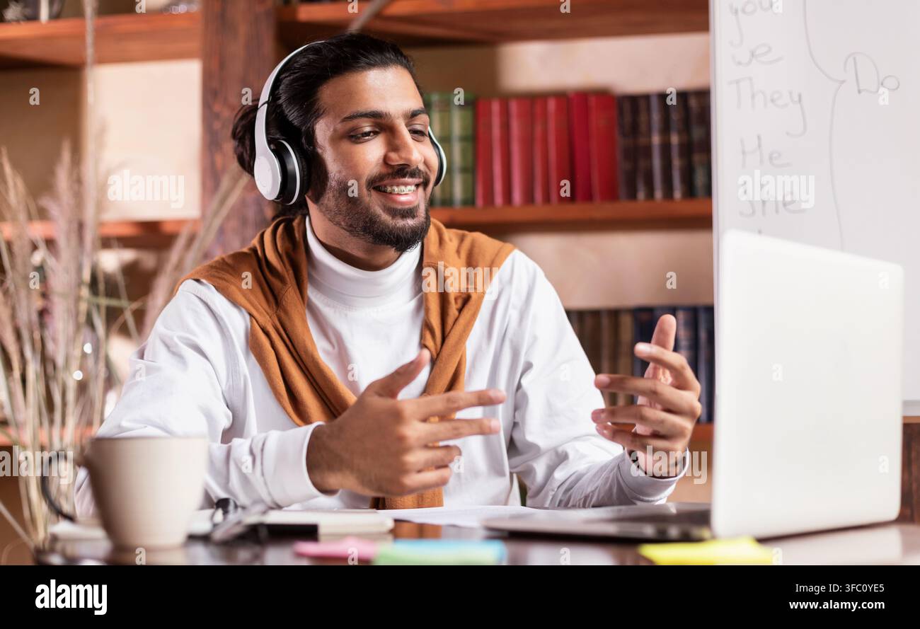 Tuteur indien joyeux ayant une classe virtuelle assis à Laptop Indoor Banque D'Images
